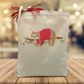 Holiday sloth printed on a canvas tote bag sitting on a table with a blurred background