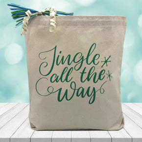 jingle all the way printed in blue on a canvas tote bag sitting on a wood table