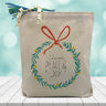 Love, Peace & Joy inside of a wreath printed on a canvas tote bag sitting on a wood table
