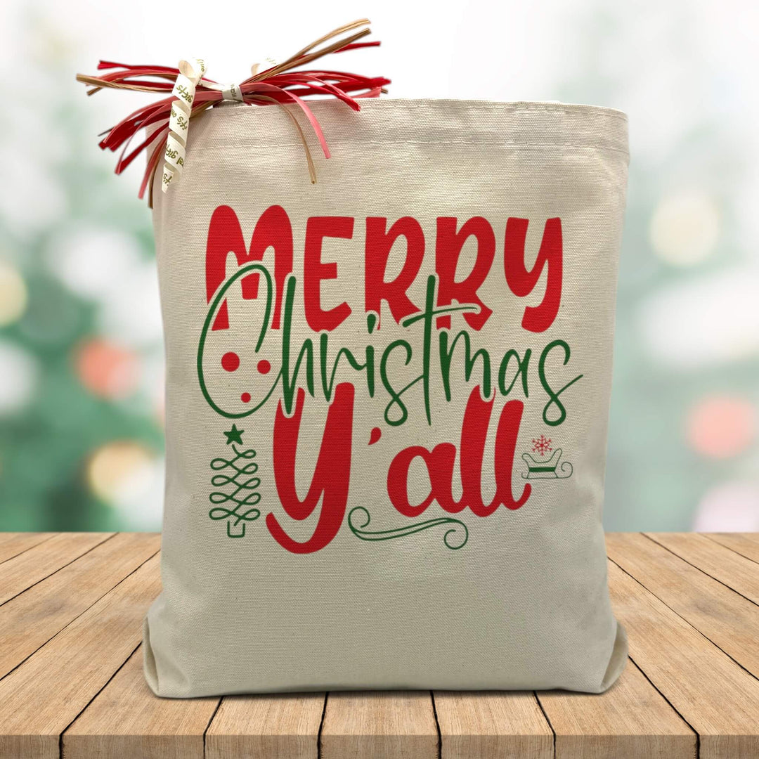 merry christmas yall in red and green printed on a canvas tote bag sitting on a wood table