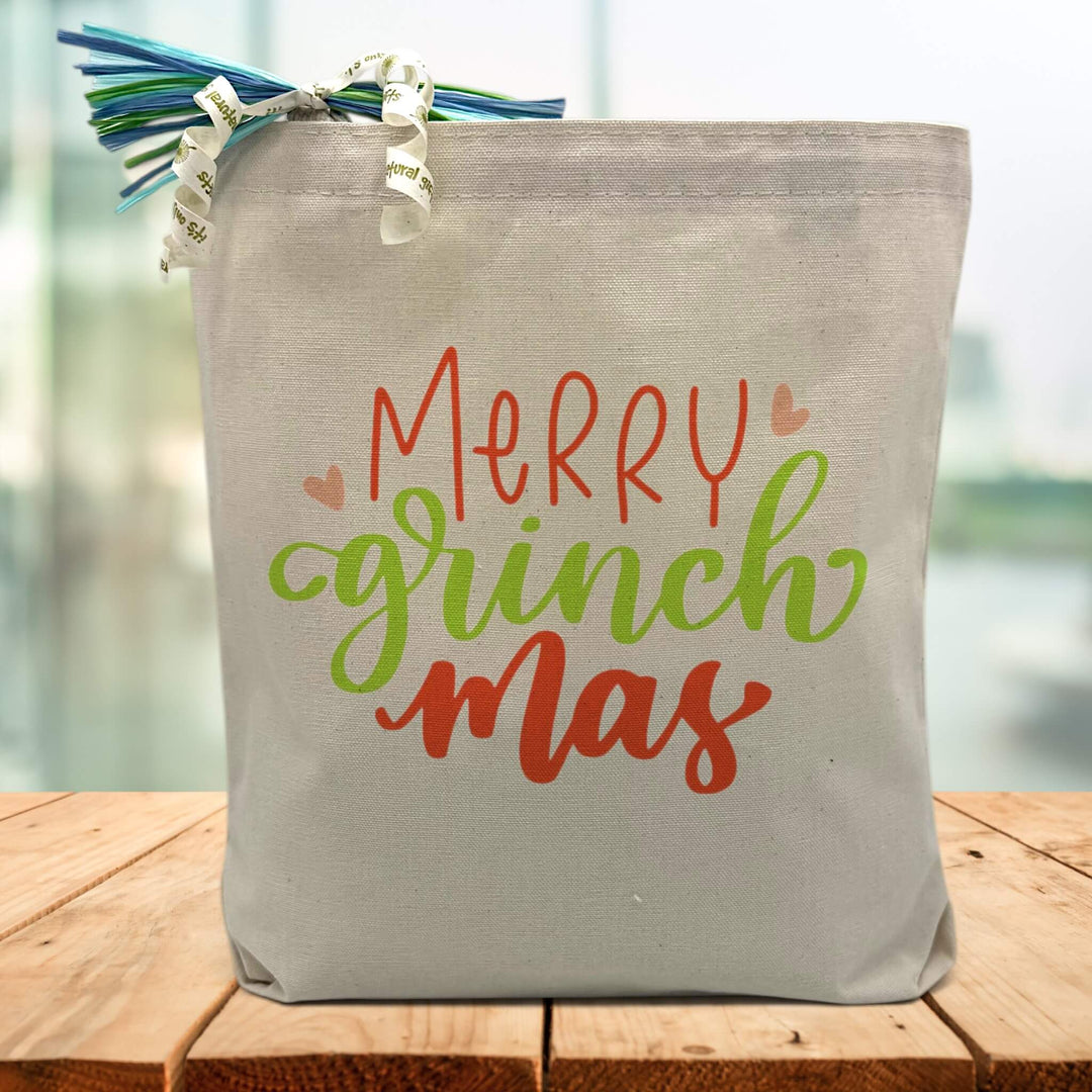 Merry Grinchmas in red and green printed on a canvas tote bag sitting on a wood table
