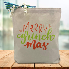 Merry Grinchmas in red and green printed on a canvas tote bag sitting on a wood table