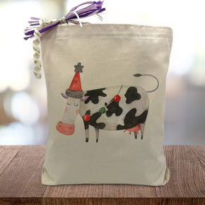 Holiday themed cow printed on a canvas tote bag sitting on a wood table