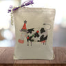 Holiday themed cow printed on a canvas tote bag sitting on a wood table