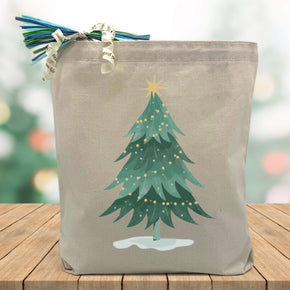 christmas tree printed on a cavnas tote bag sitting on a table with a blurred christmas tree background