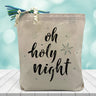 oh holy night printed on a canvas tote bag sitting on a wood table with a blurred blue background