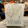 custom balloon numbers with years printed under on a canvas tote bag sitting on a rustic table