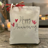 the script happy anniversary with hearts printed on a canvas tote bag sitting on a rustic table
