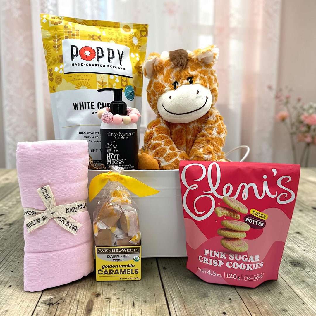 white tin tub with popcorn, baby shampoo, teething ring, swaddle, caramels and cookies