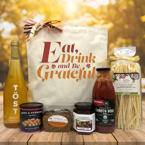 gourmet fall gift basket with sparking juice, peanuts, bread, jam, pasta and pasta sauce sitting on a table