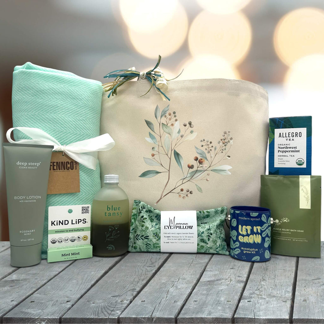large tote bag with a blanket, lotion, chapstick, bubble bath, an eye pillow, grow kit, bath soak and peppermint tea