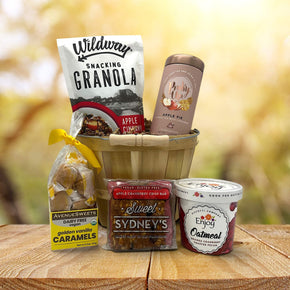 Gourmet fall gift basket with granola, tea, caramels, cranberry bar and oatmeal sitting on a table