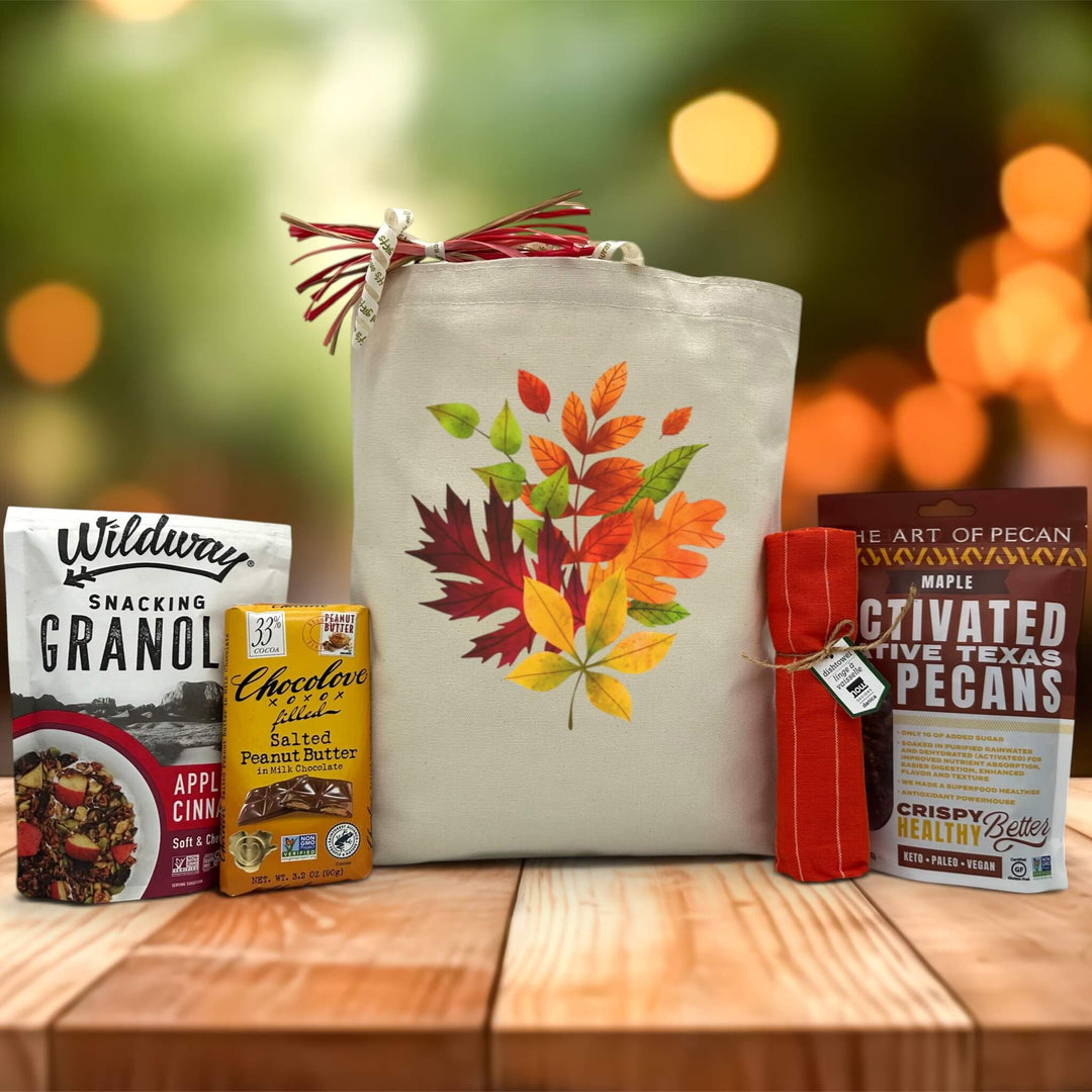 gourmet fall leaves gift with granola, chocolate, distowel, and maple pecans sitting on a table with a blurred fall background