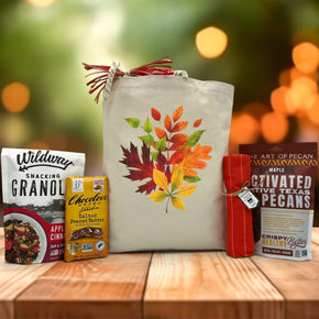 gourmet fall leaves gift with granola, chocolate, distowel, and maple pecans sitting on a table with a blurred fall background
