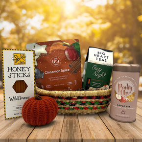 handwoven small basket with honey and 3 different teas and a knit pumpkin sitting on a table with a blurred background
