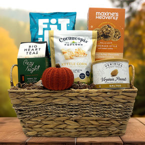 wicker basket filled with pretzels, cookies, tea, popcorn, peanuts and a knit pumpkin sitting on a table
