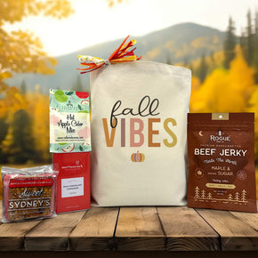 gourmet fall vibes gift basket with a sweet bar, apple cidar packet, cocoa, and beef jerky sitting on a table