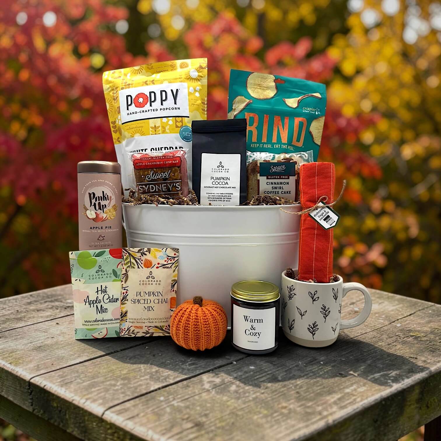 large white tin tub with popcorn, apple chips, cocoa, apple cranberry bars, tea, cider and pumpkin mix, candle mug and more