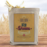 A yellow text filled box saying follow your dreams they will lead you to happiness on a canvas tote bag, placed on a table with a field in background. 
