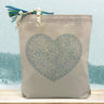 snowflake blue heart printed on a canvas tote bag sitting on a table with a snowflake background