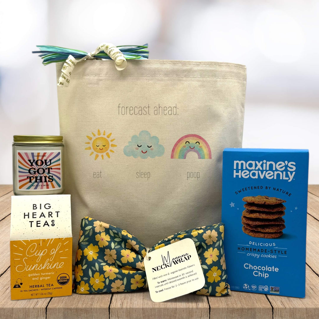 forecast ahead with sun, cloud, and rainbow printed on tote bag with candle, tea, neck wrap and cookies on table