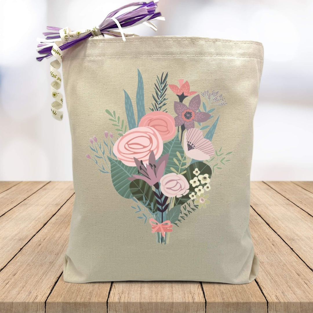 pink and blue flower bouquet printed on canvas tote bag sitting on table with white blurred background