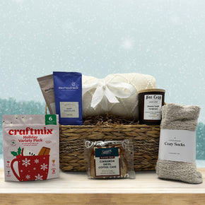 wicker basket with cocoa, holiday juice mix, blanket, candle, socks and bread