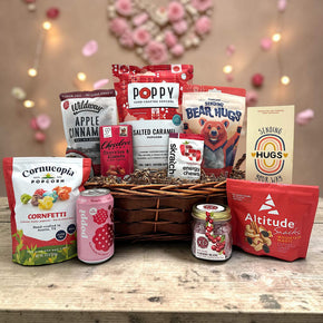wicker basket with granola, chocolate, popcorn, trail mix, drinks, energy chews, and more