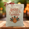 Gobble til you wobble with a turkey printed on a canvas tote bag sitting on a table with a blurred background