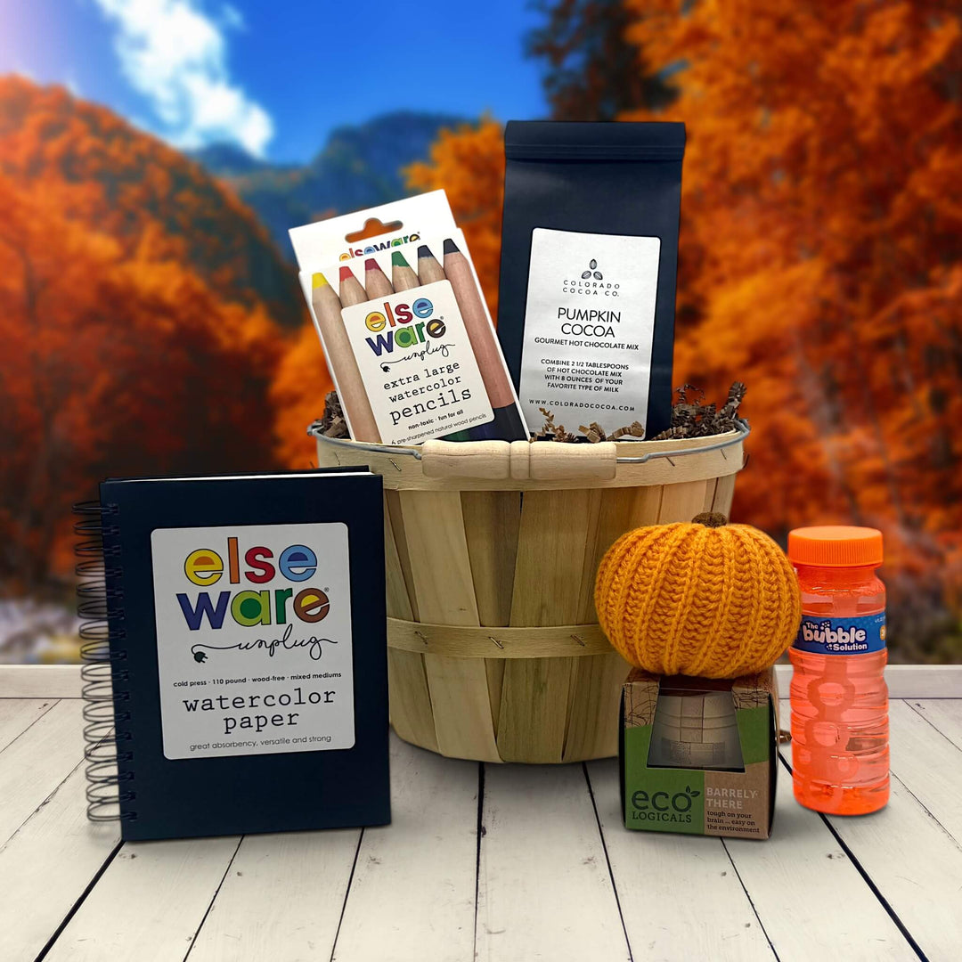 kid halloween gift basket with a watercolor paper pad, pencils cocoa, knit pumpkin, puzzle and bubbles
