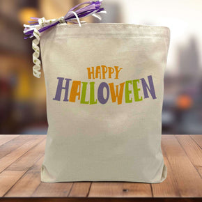 Happy Halloween printed in orange green and purple on a canvas tote bag sitting on a table