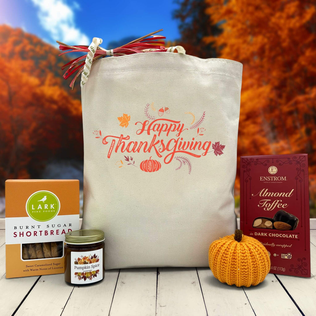 Gourmet Thanksgiving gift basket with cookies, candle, knit pumpkin and almond toffee sitting on a table