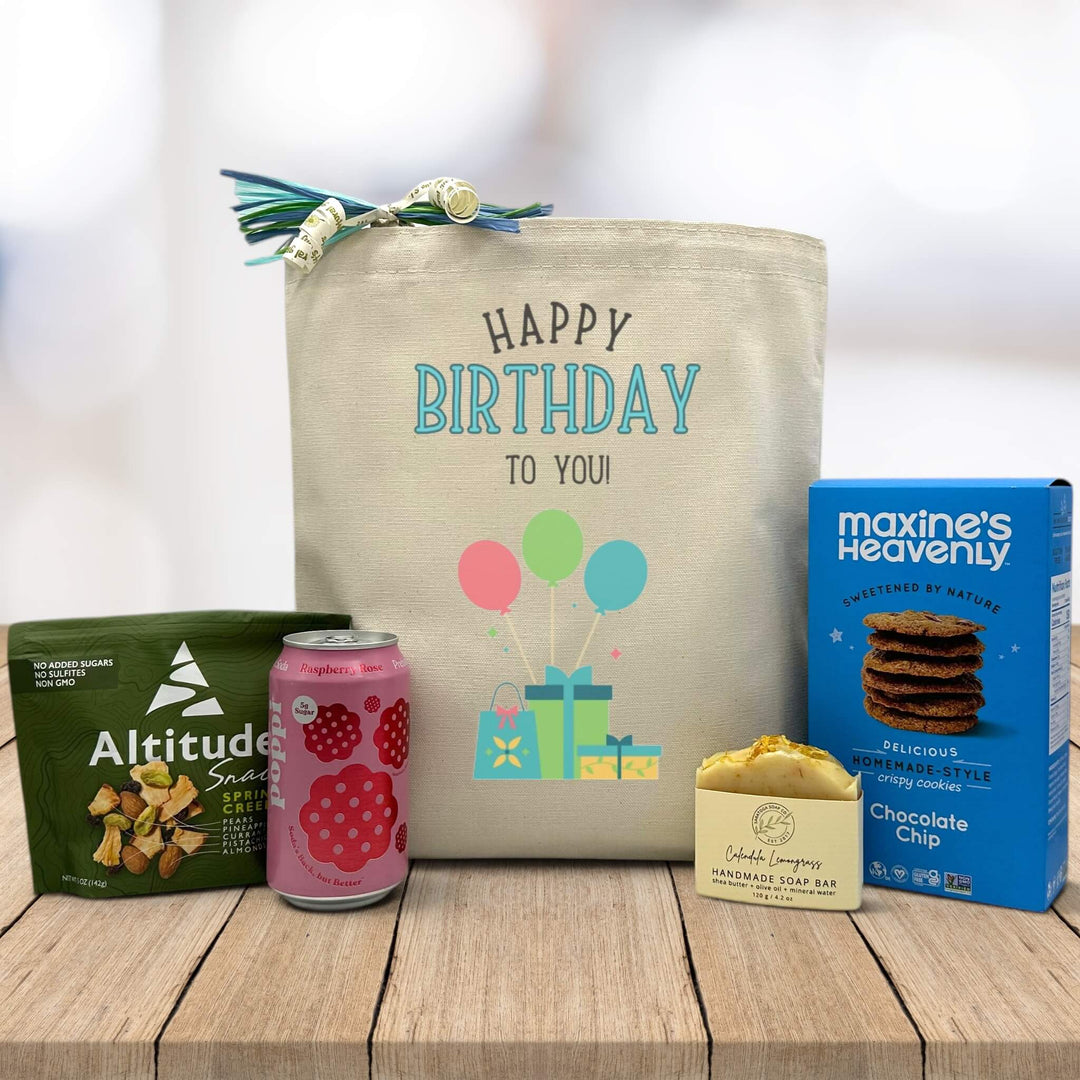 happy birthday to you written on tote bag sittign on table with trailmix, poppi soda, lemon soap, and chocolate chip cookies
