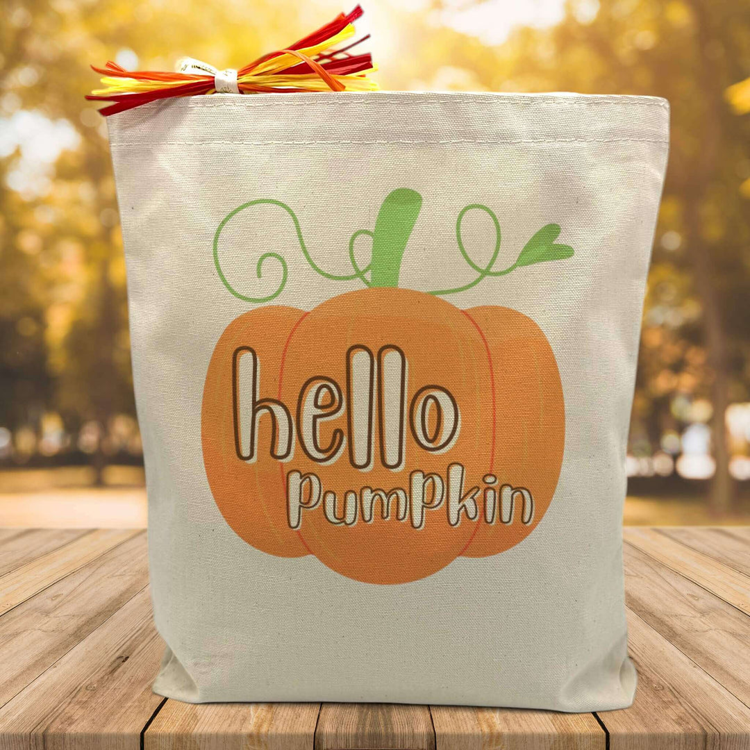 orange pumpking with hello pumpking script inside printed on a canvas tote bag sitting on a table