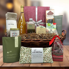 gourmet holiday gift basket with a blanket, sparkling juice, caramels, lotion, soaps, bath salts, caramel, eye pillow, and more