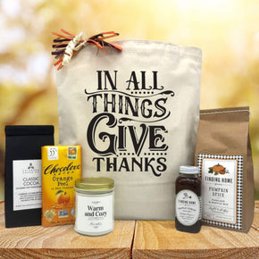 Gourmet thanksgiving basket with cocoa, chocolate, a candle, and pancake mix with syrup sitting on a table