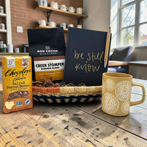 Handwoven basket with a chocolate bar, coffee, a journal and a mug