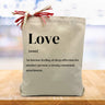 definition of love printed on a canvas tote bag sitting on a wood table with a blurred white background