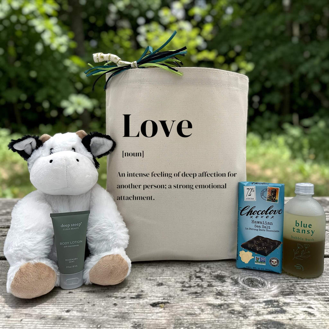 love definition gift with a stuffed cow, hand cream, chocolate bar, and bubble bath