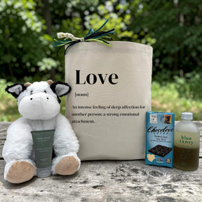 love definition gift with a stuffed cow, hand cream, chocolate bar, and bubble bath
