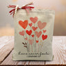 corinthians 13:8 love never fails printed on a canvas tote bag with hearts sitting on a rustic table
