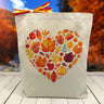 fall leaves themed heart printed on a canvas tote bag sitting on a table with a blurred fall background