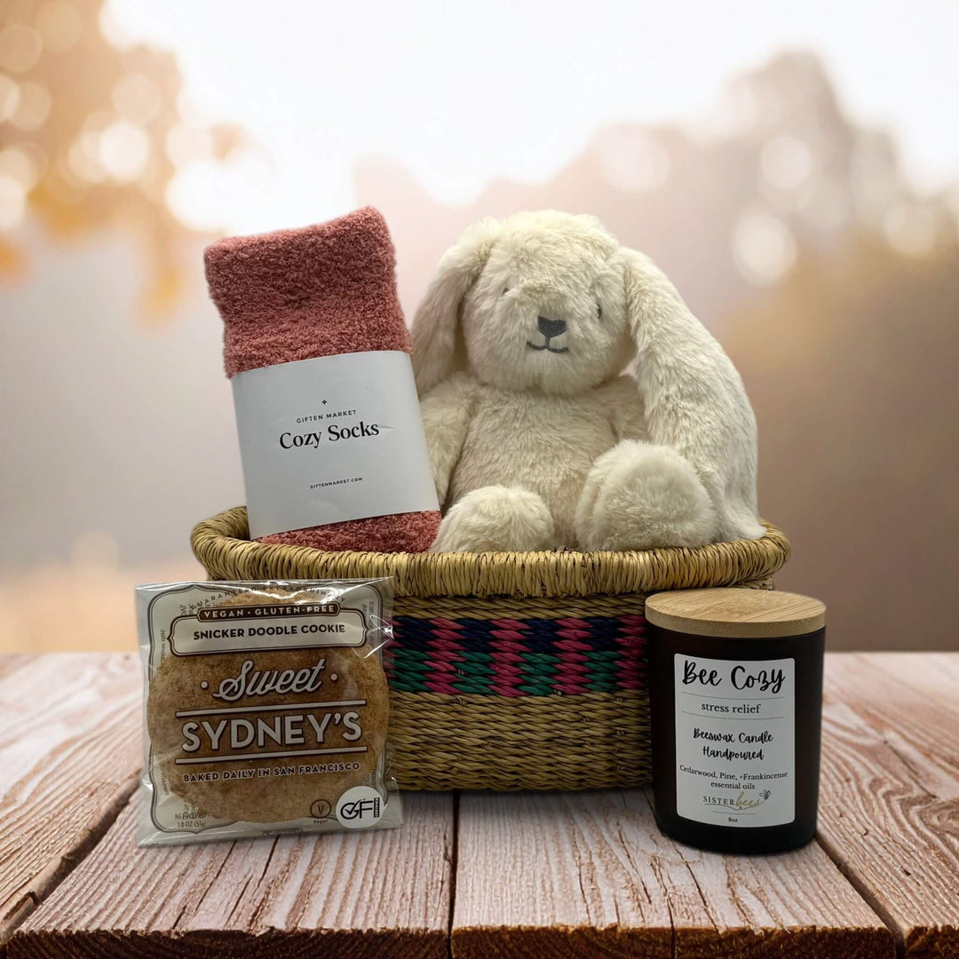 socks, bunny sitting in an african market basket with a cookie and bee cozy candle sitting on a table