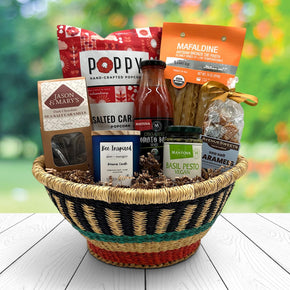 handwoven basket with popcorn, pasta, pasta sauce, caramels, candle, pesto and more caramels