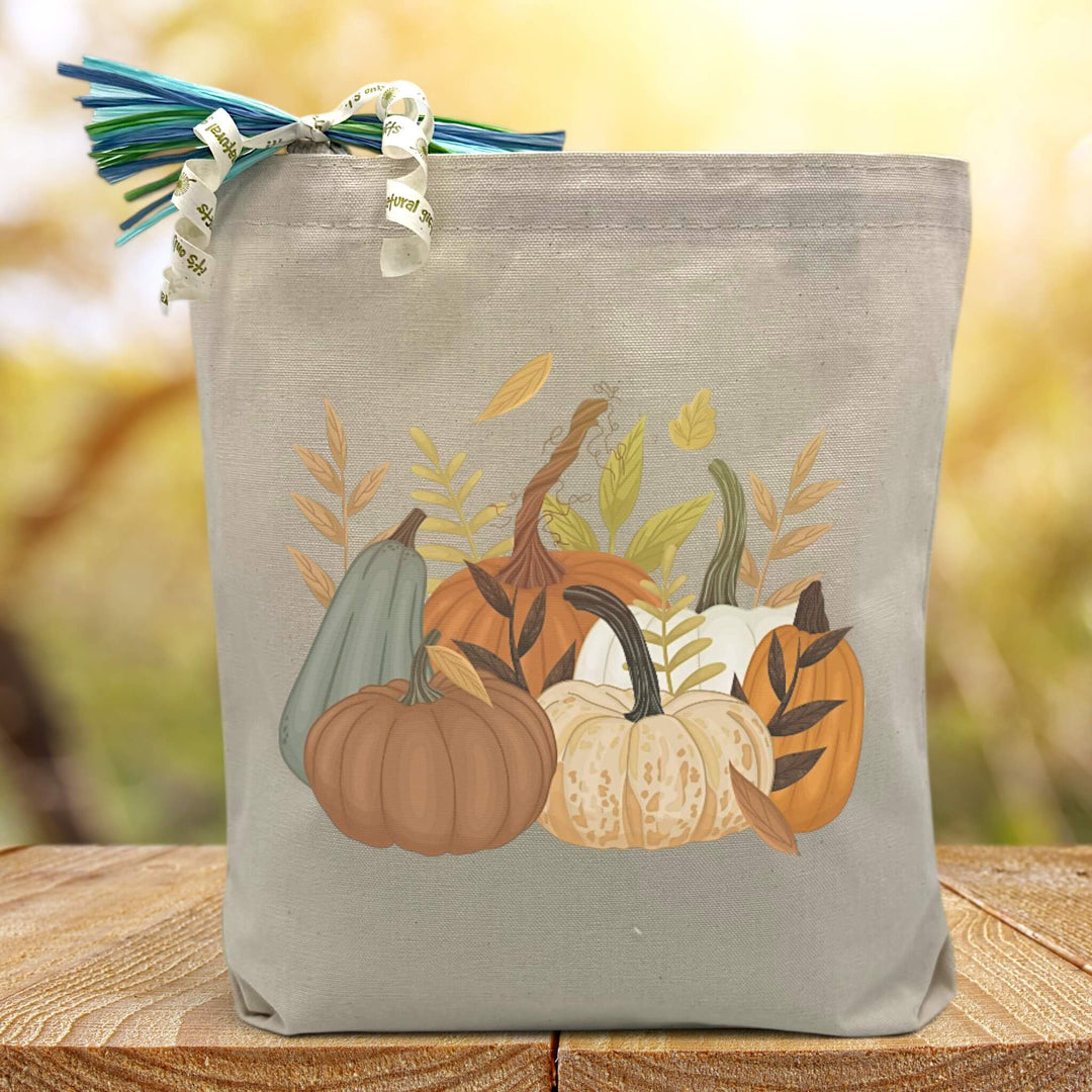 multiple types of pumpking with wheat printed on a canvas tote bag sitting on a table with a blurred background