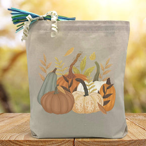 multiple types of pumpking with wheat printed on a canvas tote bag sitting on a table with a blurred background