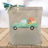 teal truck with pumpkins in the trunk printed on a canvas tote bag sitting on a table with a blurred white background