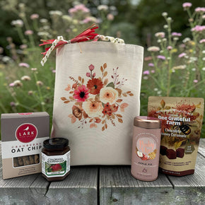 Floral gift basket with cookies, jam, tea, and caramels