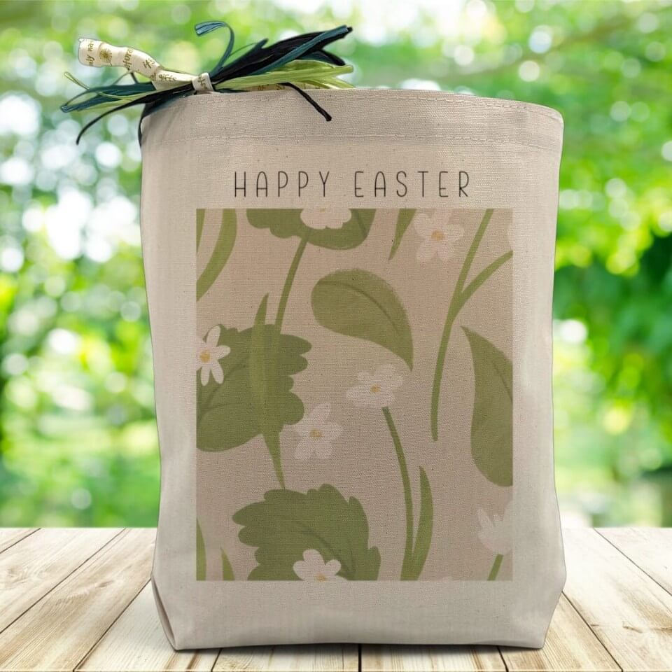 Happy Easter with a floral print on a canvas tote bag sitting on a wood table with a blurred green background