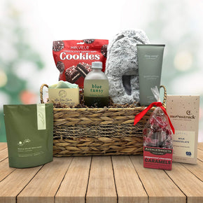 wicker basket with cookies, slippers, soap, bubble bath, lotion, bath salts, caramels, and a chocolate bar